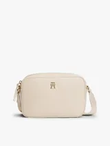 Cartera bandolera de poliuretano color beige, de diseño estructurado con compartimento principal con cierre, bolsillo interior y correa ajustable. Cuenta con el logo metalizado de la marca en el frente y detalles dorados.