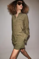 Camisa fluida de mujer de la ZW Collection de Zara, confeccionada en mezcla de viscosa, con diseño a rayas en tonos verde militar y marrón oscuro. Presenta cuello solapa, manga larga con puños anchos terminados en ribete negro a contraste, bolsillo de parche en el pecho con ribete a juego, bajo redondeado y cierre frontal con botones oscuros.