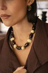 Collar corto compuesto por cuentas alternadas de cerámica en color crema y acrílico en tono borgoña oscuro, con pequeñas cuentas separadoras en piedra natural.