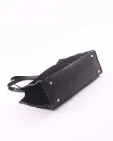 Bolso tipo shopper de gran tamaño, confeccionado en cuero gamuzado color marrón. Presenta estructura rectangular con bordes reforzados en cuero liso oscuro, doble asa de hombro y cierre mediante botón magnético.