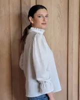 Blusa de algodón color azul, de corte suelto, con mangas largas abullonadas y cuello con volados y escote en V.