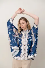 Camisa de seda modelo pañuelo, de color amarillo con estampado estilo mandala y flores, cuello redondo y cierre frontal con botones.