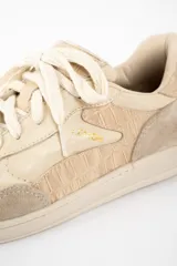 Zapatilla de cuero legítimo en tonos beige, con diseño combinado que incluye paneles de cuero liso, cuero con textura de reptil y detalles de gamuza en la puntera y el talón. Cuenta con cordones al tono y suela de goma.