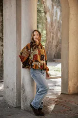 Kimono de lino con diseño patchwork en tonos rojizos y oscuros, con cuello camisero, cierre frontal de botones, mangas largas abullonadas y ruedo con volados.