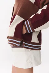 Cardigan de punto con diseño de bloques de color en tonos marrón, beige y verde. Presenta cuello redondo, cierre frontal con botones, mangas largas con hombros caídos y logo bordado en el frente.