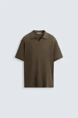 Polo de manga corta color marrón oscuro, con cuello solapa y abertura frontal en forma de V. Tejido con textura jacquard de patrón geométrico sutil.