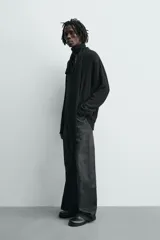 Camisa de corte relajado confeccionada en una mezcla de viscosa y algodón con textura. Presenta cuello solapa, cierre frontal de botones, manga larga con puños abotonados y aberturas laterales en el bajo.