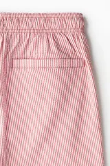 Short de baño de sirsaca con diseño a rayas verticales en color rojo y blanco. Cuenta con cintura elástica con cordón de ajuste, bolsillos laterales, bolsillo trasero con cierre y aberturas laterales en el ruedo.