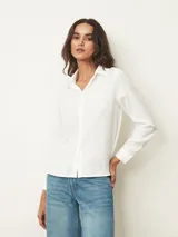 Camisa de manga larga con cuello clásico y cierre frontal de botones, confeccionada en tela con acabado satinado.