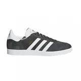 Championes adidas Gazelle de gamuza gris, con las icónicas tres bandas laterales en blanco, suela de goma blanca y detalle del nombre del modelo en dorado.