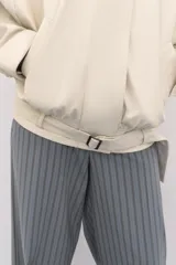 Chaqueta bomber oversize de efecto piel en color crema, con cuello subido, manga larga con hombro caído y cintura con frunces y cinturón ajustable con hebilla metálica. Cuenta con cierre frontal oculto y bolsillos laterales de vivo.