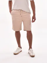 Bermuda de corte regular en color beige, confeccionada en tejido de algodón con cintura elástica y cordón de ajuste frontal. Cuenta con bolsillos laterales.