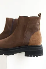 Bota corta de cuero color marrón con suela track negra y cierre lateral con cremallera.