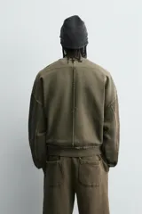 Sudadera de corte boxy fit con efecto lavado, cuello redondo con detalle de costura triangular y acabados con bordes deshilachados en el ruedo y las costuras. Presenta manga larga con puños acanalados.