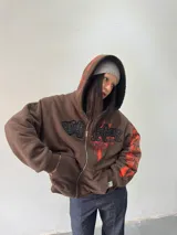Campera reversible con cierre frontal. Un lado confeccionado en algodón color marrón con estampa plastisol en color naranja, bordados con apliques y capucha. El otro lado confeccionado en tela polar de pelo largo color negro con capucha.
