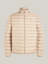 Campera acolchada color beige, con cuello alto y cierre frontal con cremallera. Tiene el logo de Tommy Hilfiger bordado en el pecho.