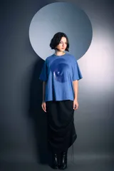 Remera de algodón color azul, de corte holgado y manga corta, con un estampado circular en tono azul más oscuro en el centro del pecho.