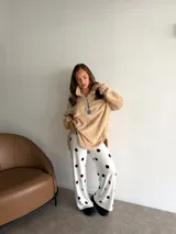 Buzo de corderito color marrón, con cuello alto y cierre frontal parcial. Presenta un diseño holgado con mangas largas y un parche decorativo en el frente.