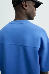 Sudadera de manga corta color marrón oscuro, con cuello redondo y bajo acabado en rib. Presenta un corte relajado y holgado (boxy fit).