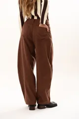 Pantalon de tiro medio con silueta curvada, mas ancha en la zona del muslo y la rodilla, con bolsillos laterales y cierre frontal con cremallera y boton.