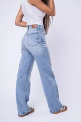 Pantalón de jean corte wide leg, de tiro alto y color azul claro lavado, con cierre y botón frontal.