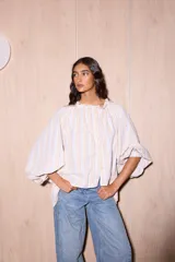 Camisa holgada de algodón con cuello alto y mangas anchas, confeccionada en Italia. Presenta un estampado de rayas verticales finas en tonos beige, blanco, amarillo, rojo y azul.