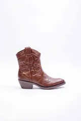 Bota texana de cuero sintético color marrón, con punta fina, taco bajo y costuras decorativas tradicionales en la caña.