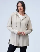 Campera color beige de modal, con cierre metálico central, capucha con cordón de ajuste y tajos laterales.