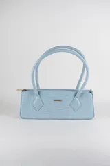 Cartera tipo baguette color celeste con textura efecto cocodrilo, diseño alargado, doble asa de hombro y cierre superior.