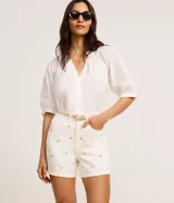 Short mom de cintura alta confeccionado en jeans color crudo, con bordado de corazones metalizados dorados, trabillas en la cintura, cierre tradicional y cinco bolsillos.