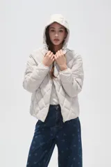 Campera acolchada de color beige con diseño capitoneado en forma de rombos, cierre frontal completo y capucha integrada.