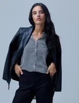 Blazer de eco cuero negro con corte oversized, cuello con solapa, cierre frontal con botones y bolsillos delanteros aplicados.