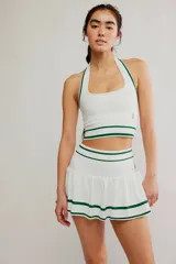 Conjunto deportivo compuesto por un top halter y una pollera pantalón de color blanco con líneas horizontales verdes.