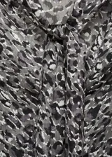 Blusa de manga larga abullonada con estampado de leopardo en tonos grises y negros. Presenta cuello redondo con cierre de lazo.