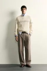 Jersey relaxed fit de punto color crudo con cuello redondo, manga larga y detalles de bordados florales en contraste a lo largo del pecho y las mangas.