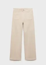 Pantalón estilo jeans de corte wideleg, color beige, con tiro medio, cierre de botón y cremallera, trabillas para cinturón y dos bolsillos de parche frontales.