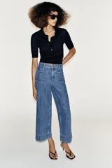Jeans culotte de tiro alto, color azul, con pernera ancha, nervios marcados en el delantero y bolsillos de parche con botones metálicos. Cuenta con cierre frontal de cremallera y botón metálico.