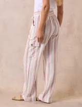 Pantalón cargo de lino a rayas verticales grises y blancas, marca Marissa Olivia. Pretina ancha elastizada con lazo de ajuste, bolsillos inclinados delanteros y bolsillos laterales con botón.