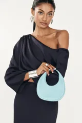 Vestido largo color azul marino, con escote asimétrico de un solo hombro y manga larga acampanada. El cuerpo superior presenta drapeado y la falda es ajustada y recta.