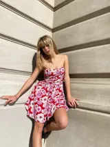 Vestido corto de gasa con estampado floral en tonos rojos, blancos y violetas. Diseño strapless con elástico en la espalda.