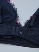 Pack de dos bralettes de encaje marca Jessica Simpson, con breteles fijos y espalda deportiva. Uno es de encaje floral color lila y el otro es de encaje floral multicolor sobre base azul.