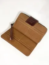 Billetera grande de cuero con detalle de pelo en el frente con estampado tipo animal print de manchas claras sobre fondo marrón, y solapa de cierre con broche y logo de búho grabado.