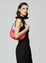 Bolso de hombro efecto cuero color rojo vibrante, con forma curva y cierre de cremallera. Presenta costuras decorativas y herrajes plateados.