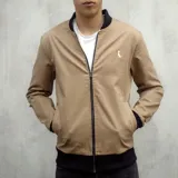 Campera bomber color caqui de gabardina, con puños y cuello negros, cierre frontal y logo bordado en blanco.