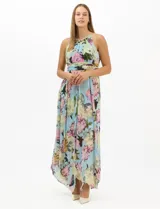 Vestido largo de chifón con estampado floral, cuello halter con pliegues y abertura tipo lágrima. Presenta una cintura drapeada que estiliza la silueta y una falda amplia con capas asimétricas y bajo en picos. Incluye forro interior y cierre invisible en la espalda.
