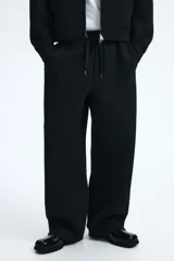 Pantalón tipo jogger de corte relajado con efecto neopreno, cintura elástica con cordón ajustable, bolsillos laterales al bies y bolsillo de parche en la parte trasera.