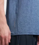 Remera deportiva masculina de manga corta con cuello redondo, confeccionada en tejido técnico con tecnología Dry para mayor transpirabilidad. Presenta detalles reflectantes en los hombros y un diseño liso en color verde melange.