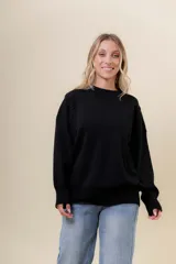 Sweater de tejido fino color beige, con cuello redondo, mangas largas y terminaciones acanaladas. Presenta un diseño con detalles trenzados en diagonal en el frente y corte relajado.