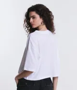 Remera cropped de manga corta, cuello redondo y calce oversized, confeccionada en tejido de algodón tipo media malla.