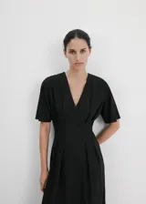 Vestido midi de corte evasé color negro, con diseño largo, cuello en pico, detalles fruncidos y manga corta. Cuenta con cierre de cremallera en la parte posterior.